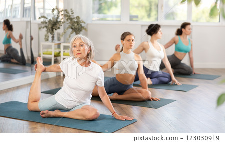 Elderly woman doing yoga in group in studio 123030919
