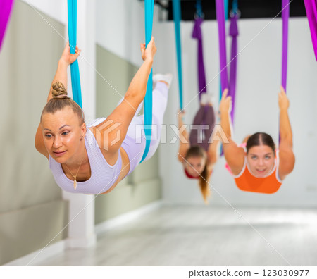 Woman performing Salabhasana asana in hanging hammock during aerial yoga training Woman performing Salabhasana asana in hanging hammock during aerial yoga training 123030977