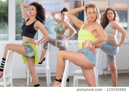 Putting foot hand on seat of chair, girl improvises, perform lap dance during group master class Putting foot hand on seat of chair, girl improvises, perform lap dance during group master class 123030988