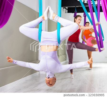 Woman doing inverted bound angle pose in hanging hammock with fingers in mudra 123030995
