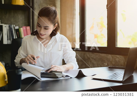 A professional, successful Asian female architect boss is working on a project at her desk. 123031381