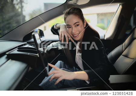 A beautiful, successful Asian businesswoman is adjusting something on a screen of her car. 123031428