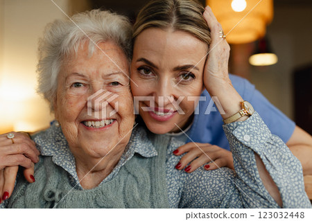 Portrait of caring healthcare worker visiting a senior patient at home, hugging her. 123032448