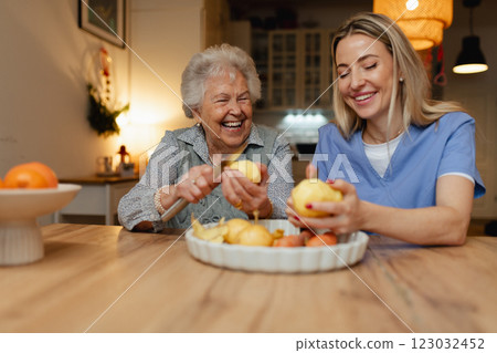 Portrait of elderly companion assistant and senior woman peeling potatoes. Home health care services. 123032452