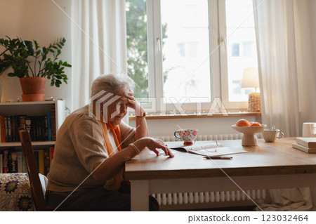 Elderly woman looking sadly at few banknotes on table. Concept of financial concerns for seniors. 123032464