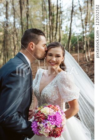 Portrait of beautiful bride and an elegant groom in nature, surrounded by a forest. 123032582