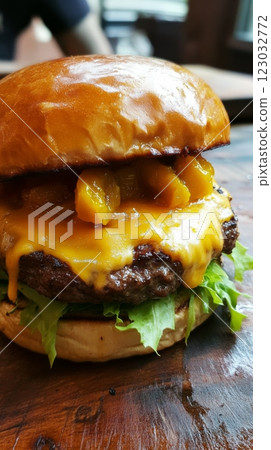 A burger with a juicy beef patty, melted cheese and yellow mango pickle, served on a golden bun. Vertical close-up image 123032772