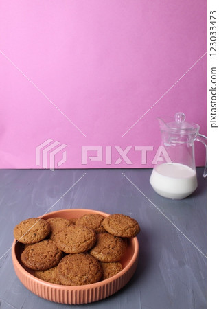 Oatmeal cookies in a plate of a jug of milk on a gray pink background with space for copyspace text. The concept of a delicious afternoon snack 123033473