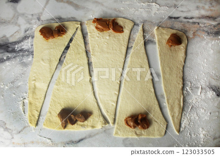 triangles of dough with boiled condensed milk. Making croissants, buns, biscuits triangles of dough with boiled condensed milk. Making croissants, buns, biscuits 123033505