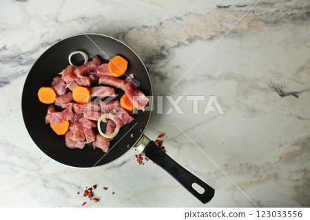 Pieces of raw pork meat and vegetables, onions, carrots in a pan, top view copyspace Pieces of raw pork meat and vegetables, onions, carrots in a pan, top view copyspace 123033556