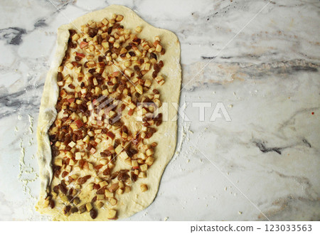 Wraps a layer of yeast dough filled with apple, raisins in a roll. Space for copyspace text Wraps a layer of yeast dough filled with apple, raisins in a roll. Space for copyspace text 123033563