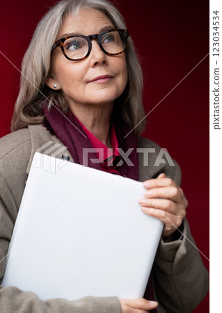 Elderly businesswoman contemplating her next steps while holding a portfolio at a corporate event in 123034534