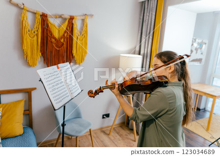 Focused young artist playing violin and studying music composition A dedicated violin student practices classical compositions, focusing on precision and technique Focused young artist playing violin and studying music composition A dedicated violin student practices classical compositions, focusing on precision and technique 123034689