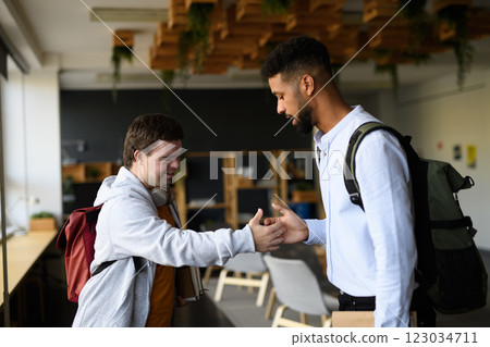 Young man with Down syndrome greeting his teacher in school. Young man with Down syndrome greeting his teacher in school. 123034711