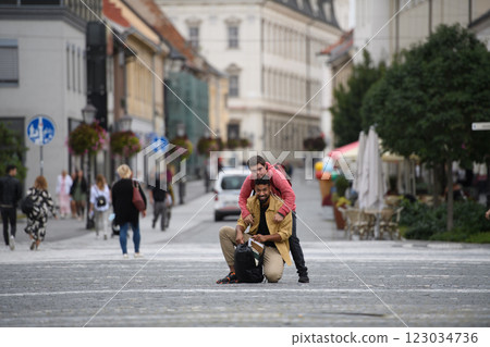 A young man with Down syndrome and his mentoring friend walking across city, talking. A young man with Down syndrome and his mentoring friend walking across city, talking. 123034736