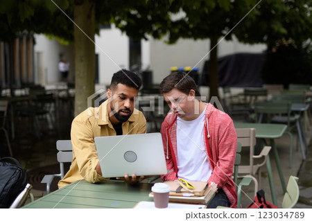 Young man with Down syndrome studyng with special educator teacher, using laptop. Young man with Down syndrome studyng with special educator teacher, using laptop. 123034789