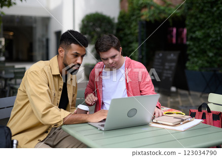 Young man with Down syndrome studyng with special educator teacher, using laptop. Young man with Down syndrome studyng with special educator teacher, using laptop. 123034790