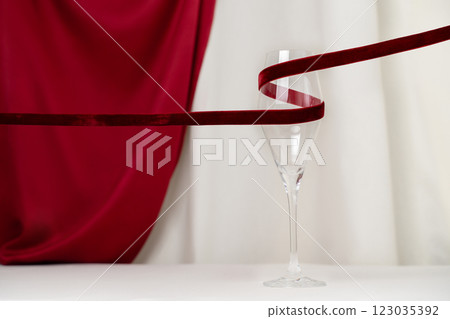 A minimalist and creative composition featuring a wine glass, red velvet ribbon on a soft cream and red silk background, representing elegance, Valentines celebration, and sophisticated design. A minimalist and creative composition featuring a wine glass, red velvet ribbon on a soft cream and red silk background, representing elegance, Valentines celebration, and sophisticated design. 123035392