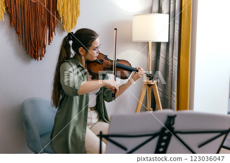 Focused young artist playing violin and studying music composition A dedicated violin student practices classical compositions, focusing on precision and technique 123036047