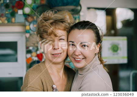 Elderly woman and young woman hug each other while smiling warmly. The generational connection is evident in their expressions of joy and tenderness. Elderly woman and young woman hug each other while smiling warmly. The generational connection is evident in their expressions of joy and tenderness. 123036049