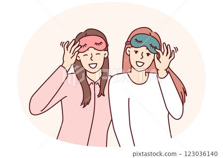 Two friendly girls in pajamas with sleep masks are preparing to relax in comfortable bedroom Two friendly girls in pajamas with sleep masks are preparing to relax in comfortable bedroom 123036140