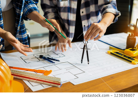 Person's engineer Hand Drawing Plan On Blue Print with architect equipment, Architects discussing at the table, team work and work flow construction concept. 123036807