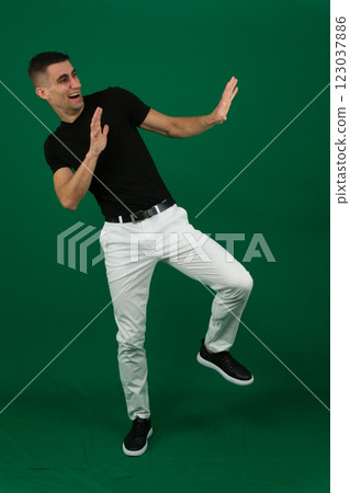 Young man celebrating success. Happy funny joyful excited guy in stylish green party suit and cool glasses raising fist up and dancing isolated on bright yellow background. Full length shot, side view Young man celebrating success. Happy funny joyful excited guy in stylish green party suit and cool glasses raising fist up and dancing isolated on bright yellow background. Full length shot, side view 123037886