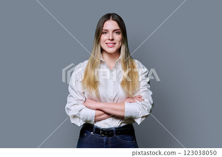 Portrait of young confident smiling woman in white shirt on gray background Portrait of young confident smiling woman in white shirt on gray background 123038050