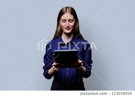Teenage female student using digital tablet on gray studio background 123038059