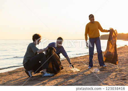 Earth day. Volunteers activists collects garbage cleaning of beach coastal zone. Woman and mans puts plastic trash in garbage bag on ocean shore. Environmental conservation coastal zone cleaning 123038416