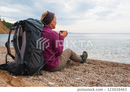 Hiking tourism adventure. Backpacker woman resting after hiking looking at beautiful view. Hiker girl lady tourist with backpack sitting near lake. Hiker woman enjoy hike tourism active vacation Hiking tourism adventure. Backpacker woman resting after hiking looking at beautiful view. Hiker girl lady tourist with backpack sitting near lake. Hiker woman enjoy hike tourism active vacation 123038463