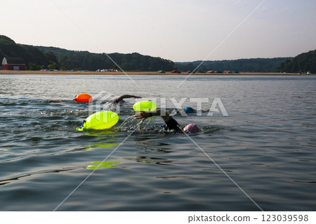 Swimmers Practice in Open Water With Bright Flotation Devices on a Sunny Day 123039598