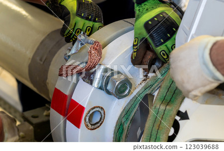 Workers dismantling a flanged pipeline connection using lifting straps and gloves. Workers dismantling a flanged pipeline connection using lifting straps and gloves. 123039688