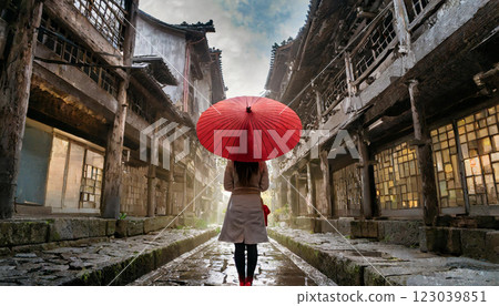 一棟古雅的亞洲建築內，一位撐著紅傘的女子在雨中 123039851