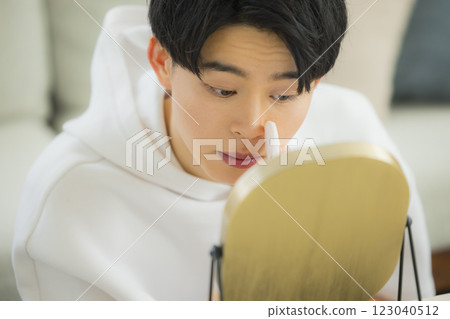 Young man looking in the mirror in his living room 123040512