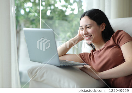 Happy asian woman using laptop sitting at home 123040969