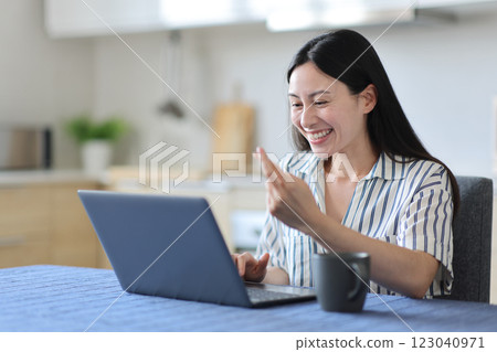 Hopeful asian woman crossing fingers checking laptop 123040971