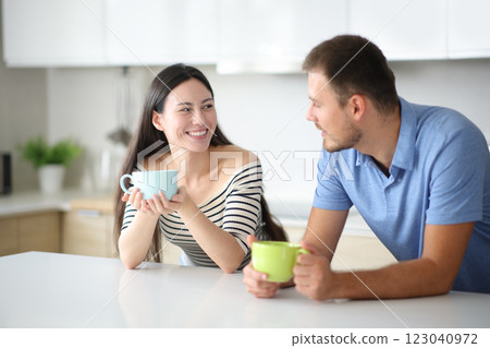 Interracial couple talking and drinking in a kitchen 123040972