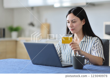 Serious asian woman buying online in a kitchen 123040978