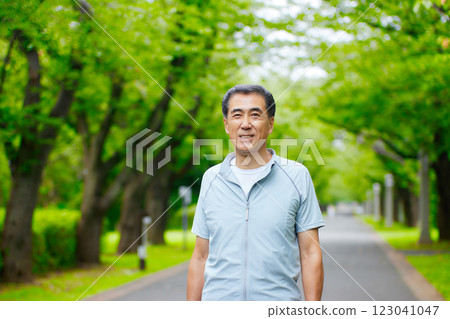 Smiling senior man standing in the greenery of a park 123041047