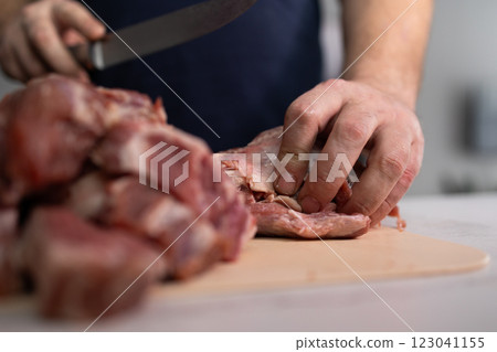 Talented Butcher Hands Skillfully Preparing Fresh Meat in a WellEquipped Kitchen Setting 123041155