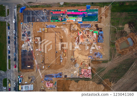Aerial view of construction site with cranes, foundations and building materials. Residential building under construction. Progress of new development in small town 123041160