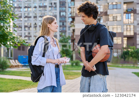 Young teenage guy and girl talking, walking together, urban background 123042174