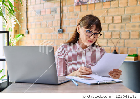Smiling middle-aged business woman reading paper letter in coworking cafe 123042182