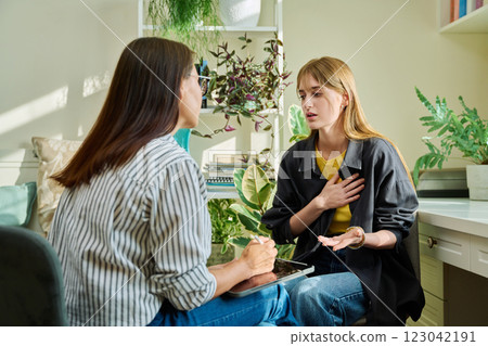 Sad upset young teenage female patient talking to professional mental therapist 123042191