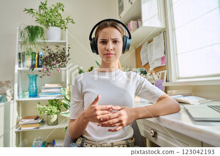 Webcam view of talking teenage girl in headphones in home room Webcam view of talking teenage girl in headphones in home room 123042193