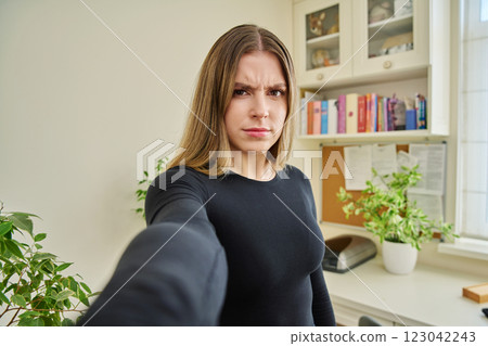 Close-up selfie portrait of teenage confused female looking at web camera 123042243