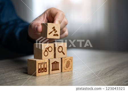 A man assembles a judicial system from blocks in the shape of a pyramid. Legal hierarchy, law enforcement, and justice system organization. A man assembles a judicial system from blocks in the shape of a pyramid. Legal hierarchy, law enforcement, and justice system organization. 123043321