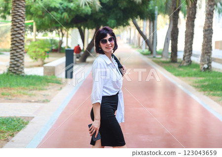 Slender mature woman on red walking carpet in city 123043659