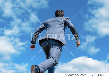 一位身穿西裝的男商人在藍天下奔跑的背影 123044718